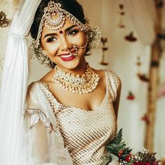 a woman in a bridal outfit holding a bouquet and smiling at the camera with her nose painted