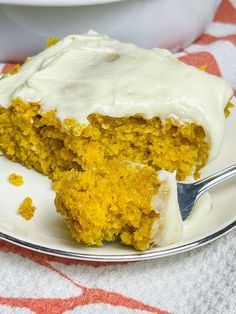 a piece of cake with white frosting on a plate and a fork next to it