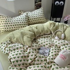 an unmade bed with green hearts on it and headphones hanging from the pillow