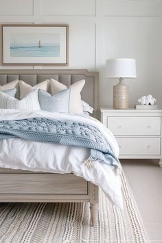 a bed with white linens and blue throw pillows on it in a bedroom setting