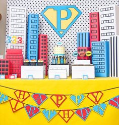 there is a cake on the table in the shape of a cityscape with a superman symbol