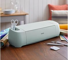 a printer sitting on top of a wooden table next to some crafting supplies and scissors