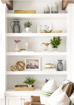 a living room filled with lots of white bookshelves covered in pictures and plants