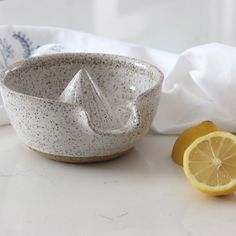 a white bowl sitting on top of a counter next to a slice of lemon and a napkin