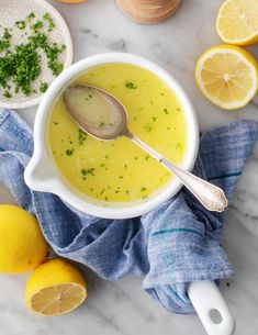 a white bowl filled with soup next to sliced lemons and other ingredients on a marble surface