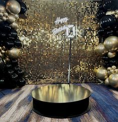 a round table in front of a wall with gold and black balloons