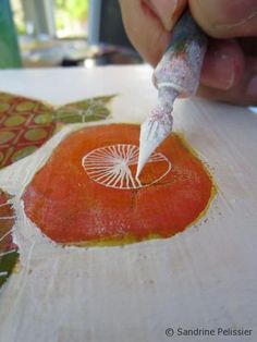 a person is using a sharpie to paint an orange piece of art on paper