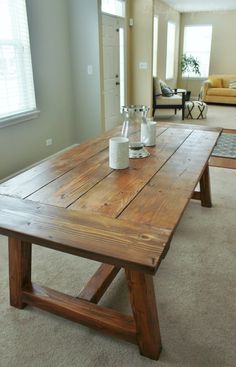 a wooden table with two vases on it in the middle of a living room