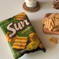 a bag of sun crackers next to a cup of coffee and plate of chips