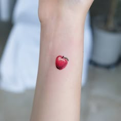 a small apple tattoo on the wrist is shown in this image, it looks like an apple