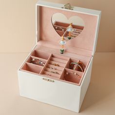 an open jewelry box with rings and bracelets in it on a beige table top