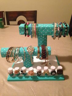 a table topped with lots of bracelets and rings on top of a blue stand