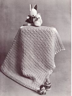 an old photo of a blanket with a stuffed animal on top