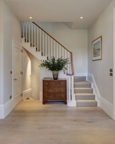 an entryway with stairs and a plant in a vase on the dresser next to it