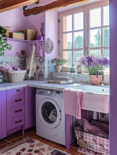 a kitchen with purple cabinets and white counter tops, an open washing machine in the center