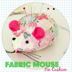 a pink mouse pin cushion sitting on top of a table next to scissors and thread