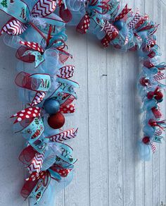 a christmas wreath hanging on the side of a white wooden wall with red and blue decorations