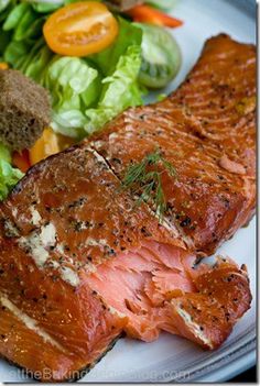 a white plate topped with meat next to a salad and lettuce covered in seasoning