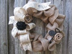 a wreath made out of burlocks and ribbon with buttons on it sitting against a wooden fence