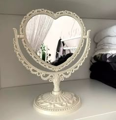 a mirror that is on top of a white shelf with clothes in the back ground