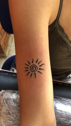 a woman's arm with a small sun tattoo on it