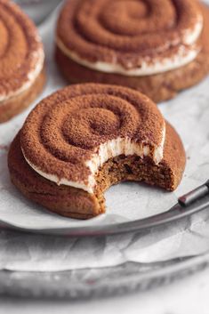 three cinnamon roll cookies on a plate with one cut in half to show the inside