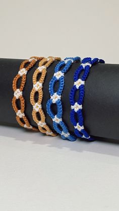 four different colored bracelets sitting on top of a black piece of cloth next to each other