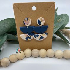 a pair of blue and white earrings sitting on top of a wooden bead necklace