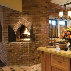 a brick oven in the middle of a kitchen with flowers on the counter and an open door leading to another room