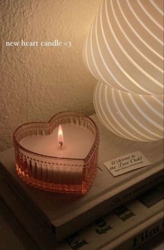 a heart shaped candle sitting on top of a book