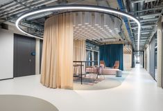 an office lobby with round tables and chairs on the floor, along with drapes covering the walls