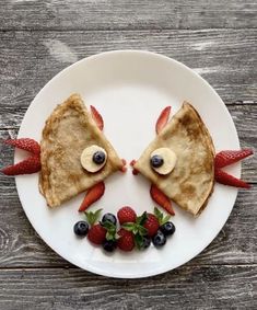 two pancakes with faces made out of strawberries and blueberries