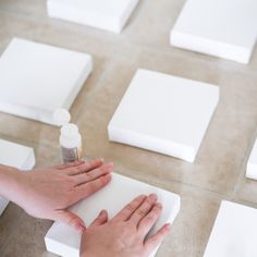 two hands reaching for something on top of some white square tiles with one person's hand