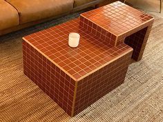 a coffee table made out of two different pieces of red tile with a white cup on top