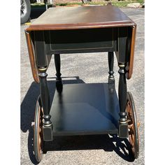 an old fashioned wooden table with wheels on the bottom and sides, sitting in a parking lot