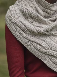 a woman wearing a white knitted shawl with red sleeves and a brown sweater