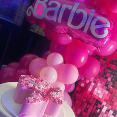 there is a cake on the table with pink balloons in the background and a sign that says barbie above it