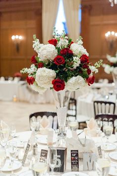 a vase filled with red and white flowers on top of a table covered in plates