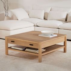 a living room with a couch, coffee table and white pillows on the floor in front of it