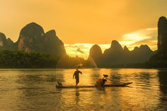 two people on a boat in the water at sunset