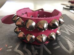 "Classic studded punk bracelet with 2 rows of 1/2\" cone studs. Fastens with a buckle and is adjustable. All hardware is nickle plated. Studs on black bracelets are nickel plated brass, studs on colored bracelets are nickel plated steel (old stock) Smaller bracelets have fewer studs per row. Made with hand dyed vegetable tan leather. Note: red bracelet is kind of pink-ish. Bracelet is 1.25\" wide. Ask about custom sizing and color options!" Adjustable Metal Bracelets With Studs, Adjustable Punk Cuff Bracelet With Rivets, Punk Adjustable Cuff Bracelet With Rivets, Punk Style Adjustable Cuff Bracelet With Rivets, Punk Studded Bracelets For Festivals, Punk Style Studded Bracelets For Festivals, Metal Studs Bracelet For Concerts, Metal Stud Bracelets For Concerts, Metal Studded Bracelets For Concerts