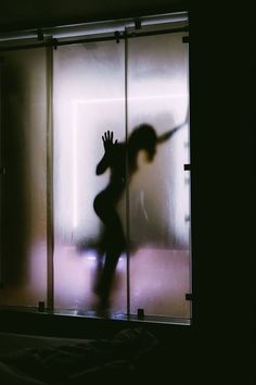 a person standing in front of a glass door with their hand up to the side