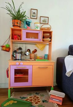 a child's play kitchen with toys on the floor in front of a couch