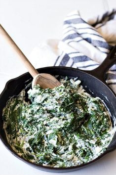 spinach dip in a skillet with a wooden spoon