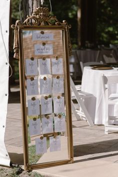 a gold framed mirror sitting on top of a sidewalk next to a white table cloth