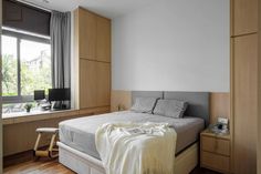 a bed sitting under a window next to a wooden floor