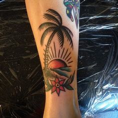 a woman's foot with a tattoo on it that has a palm tree and flowers