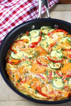 an omelet with zucchini, tomatoes and other vegetables in a pan