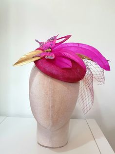 Little Hats for Grand Occasions. Customer information and sizing. Fuchsia Pink Gold Metallic sinamay hatinator base with a spray of fuchsia/gold feathers and pink butterflies. Perfect hatinator for weddings, special events, racing or a grand occasion. Embellishments, feathers, buttons and brooches are lovingly sourced for unique individual pieces. Hats are 15cm in diameter and dispatched in boxes. 2 clips and a headband are provided for ease of fixing in place.  Handmade in the UK. No two designs are the same. Please message me to discuss any personnal requirements. Return and exchanges except within 14 days. Please read the full details in the FAQS. Many more designs on the shop. Pink Luxury Short Brim Fascinator, Luxury Pink Feather Trimmed Fascinator, Luxury Pink Brimmed Fascinator, Luxury Pink Spring Fascinator, Whimsical Pink Fascinator Hat, Company Christmas Party, Holiday Hats, Gold Feathers, Wedding Fascinators