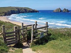 a wooden gate on the side of a hill next to an ocean and sandy beach